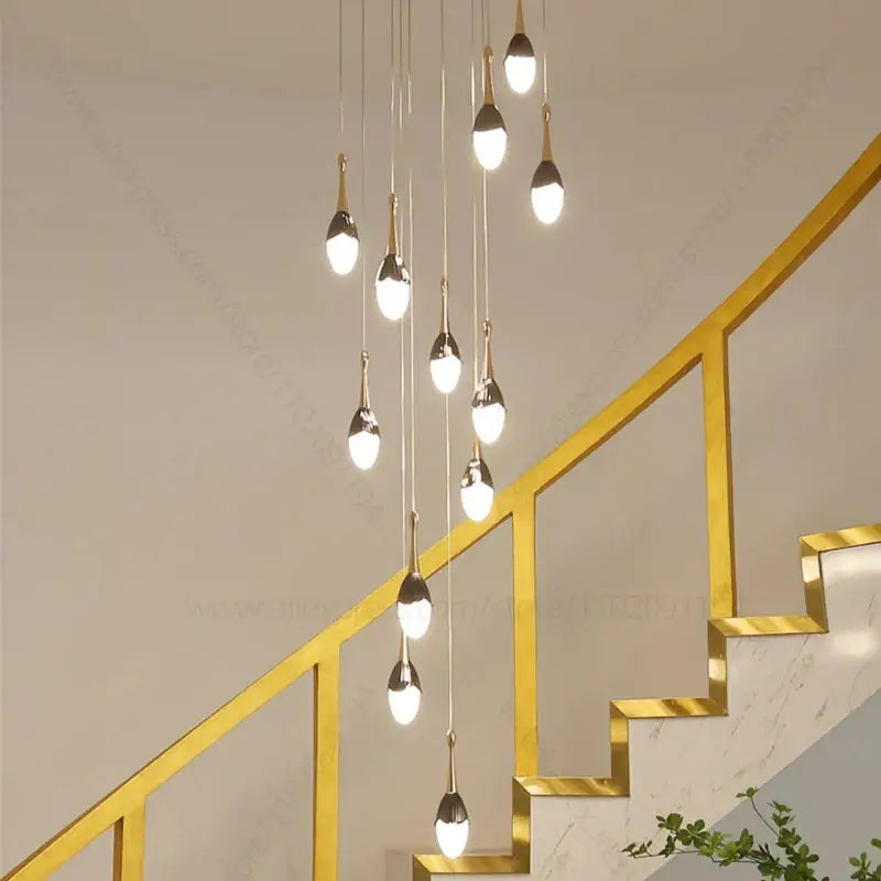 Modern gold-toned decorbites gold led staircase chandelier with teardrop glass shades hanging above stairs