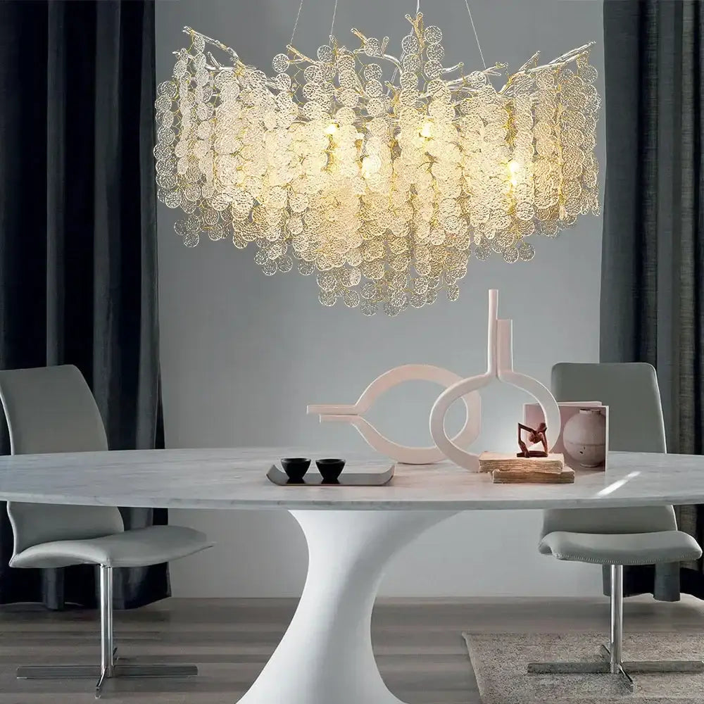 A luxury gold money tree crystal chandelier with intricate leaf metalwork hangs above a modern dining table