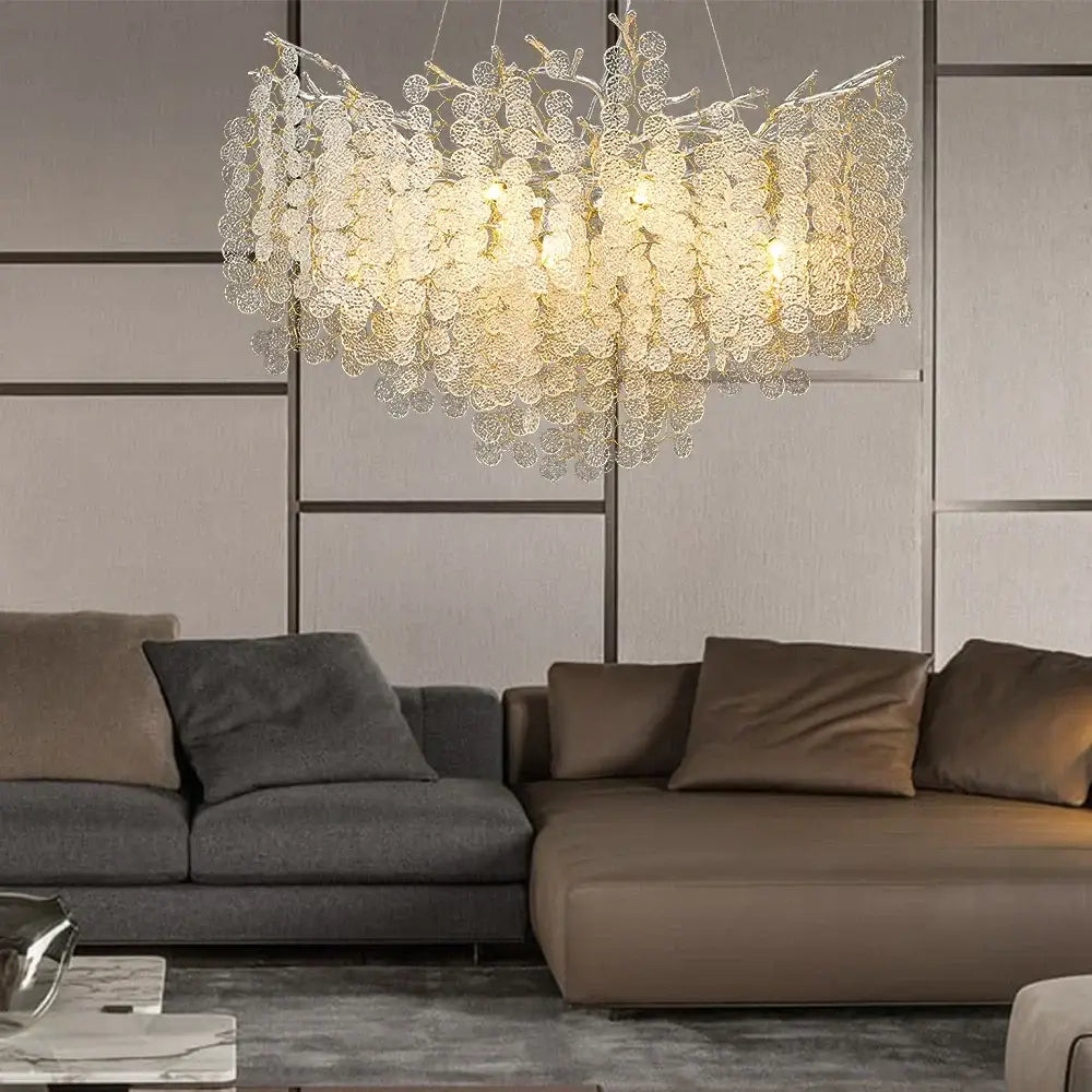 Luxury gold money tree crystal chandelier with intricate leaf metalwork and warm lights above modern sofa