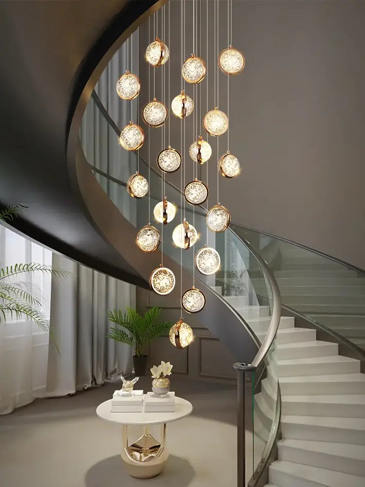 A luxury golden decorbites crystal ball led rotating stair chandelier with multiple glowing spherical glass orbs suspended by thin chains