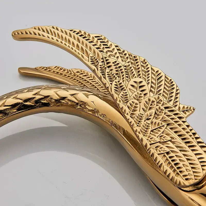 Luxury golden swan dual handle bathroom faucet with gold-toned metal bangle featuring intricate leaf and feather embossing