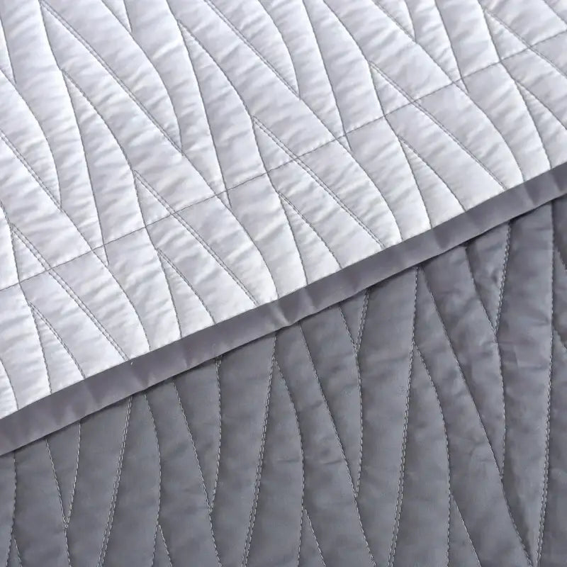 A soft quilted throw blanket with a modern gray geometric pattern from a luxury egyptian cotton quilt set