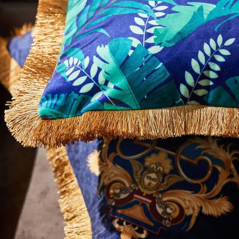 A vibrant blue velvet cushion cover with teal and white tropical leaf pattern and gold fringe from decorbites jungle animal collection