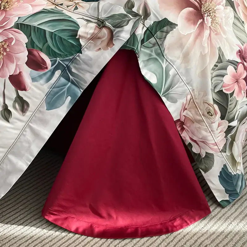 A vibrant red satin skirt with a flowing cone silhouette displayed alongside luxury pink and cream egyptian cotton flower bedding set