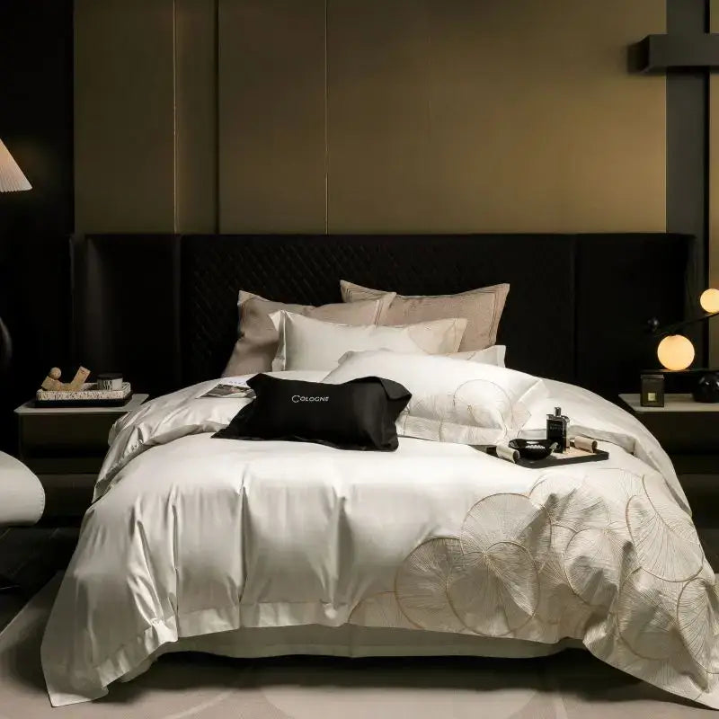 White satin duvet cover with embroidered leaf patterns and black cologne pillow in luxury cotton bedding set