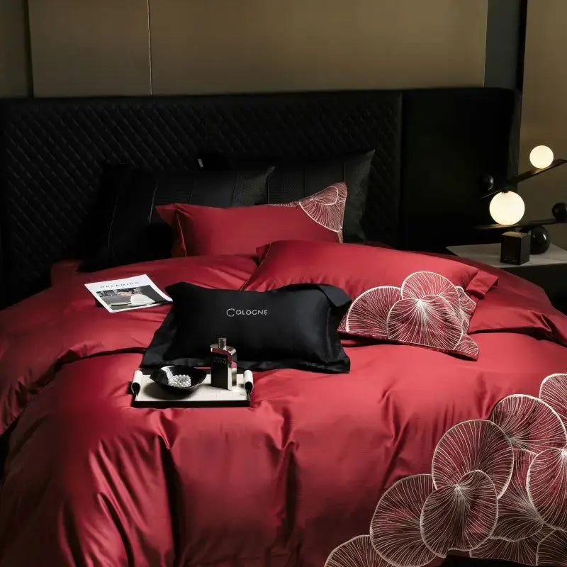 Luxury red satin cotton bedding set with white embroidered leaf patterns and black cologne logo pillow for bedroom use