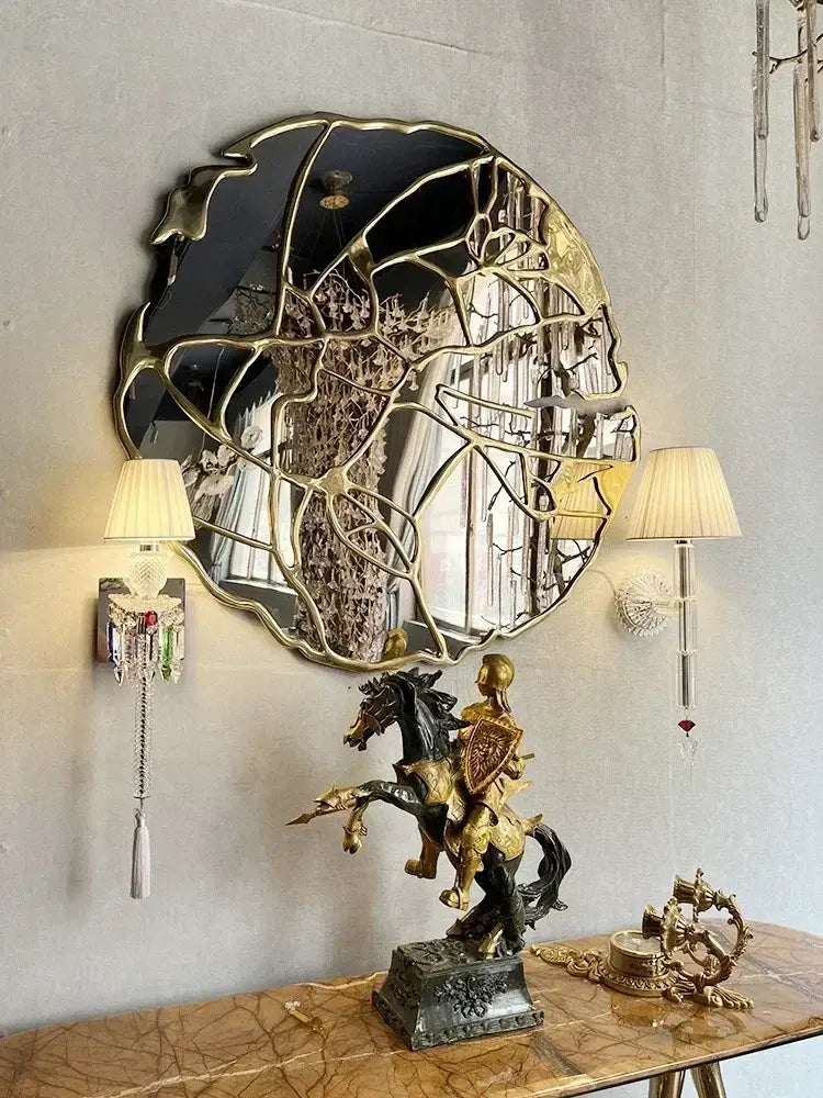 A gold-framed irregular mirror with a fragmented leaf design complementing decorbites crystal wall lamp for bedroom decor