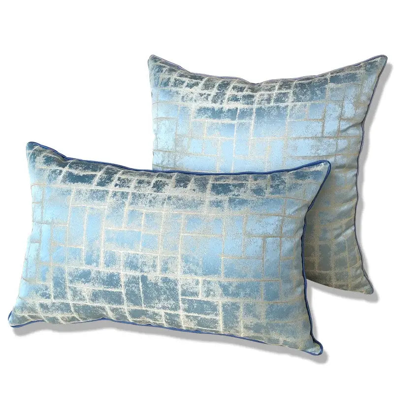 Two luxury cushion covers in light blue textured jacquard fabric with abstract grid pattern and dark blue piping edges