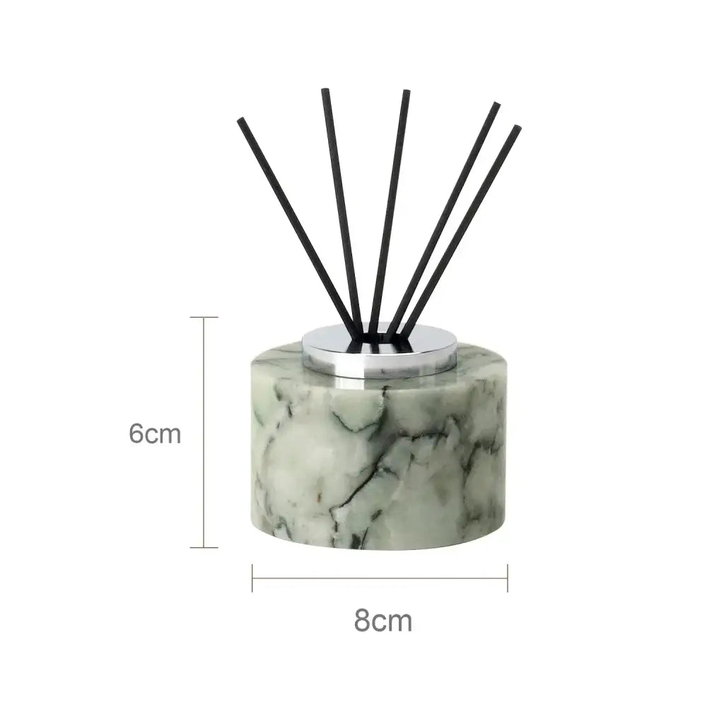 A sleek 6cm tall cylindrical reed diffuser with light green and white marble base and black reeds for emerald marble bathroom