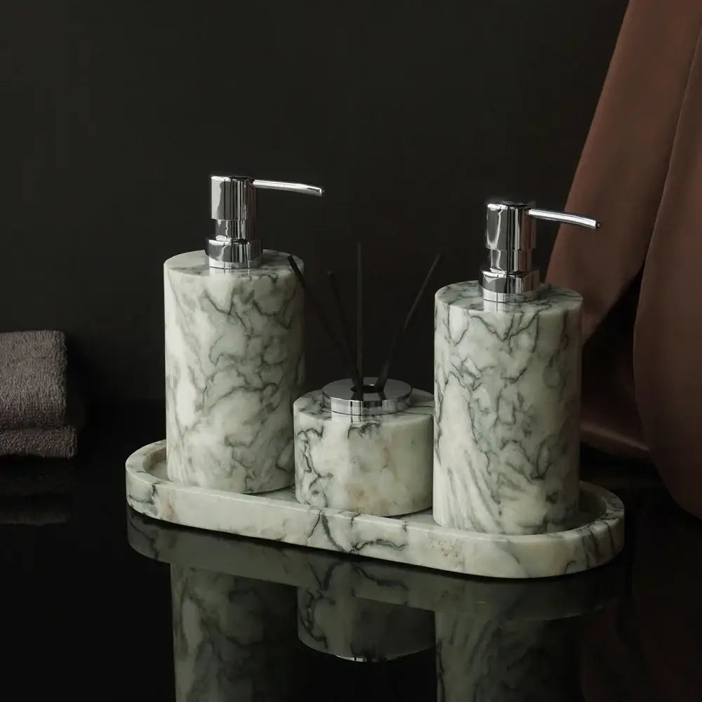Set of three elegant white marble bathroom dispensers with emerald marble veining and chrome pumps on matching tray