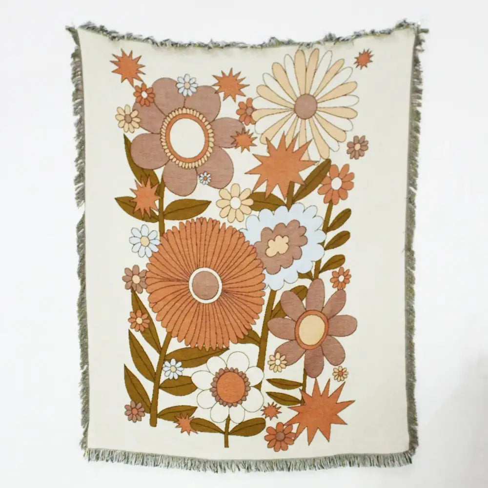 Cream-colored throw blanket with retro floral pattern and frayed edges used as geo tassel picnic mat and sofa cover