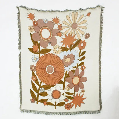 Cream-colored throw blanket with retro floral pattern and frayed edges used as geo tassel picnic mat and sofa cover