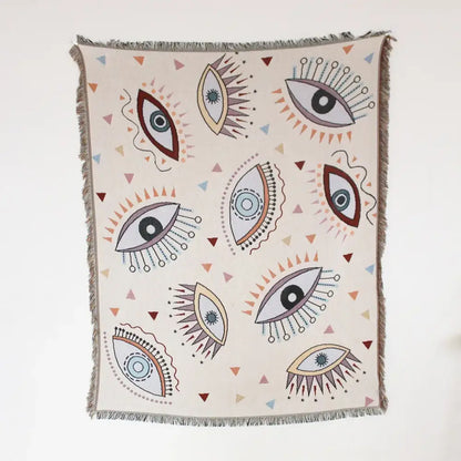Cream-colored woven sofa cover with stylized eye pattern and geo tassel accents for picnic mat and living room use