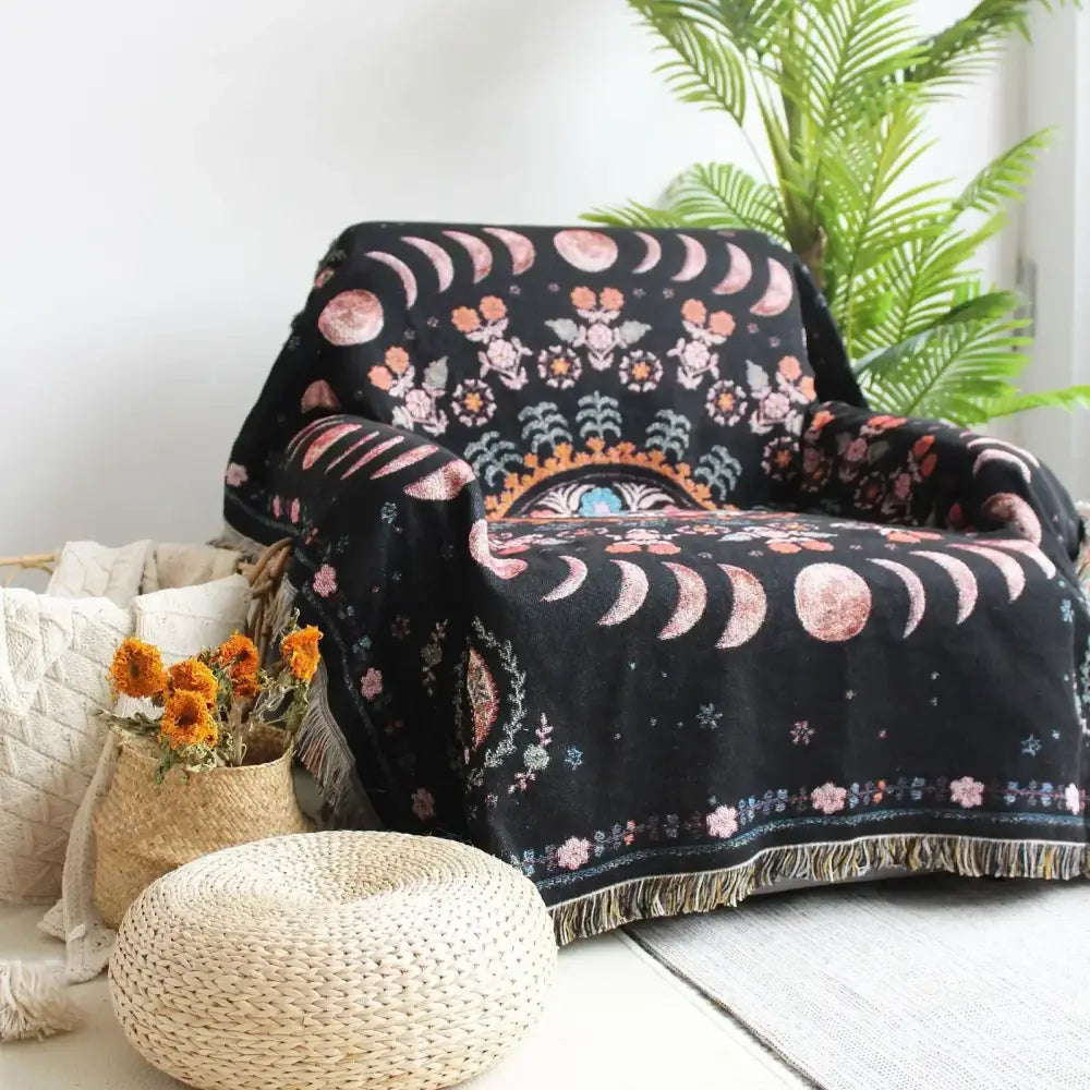 Black throw blanket with pink and gold celestial moon phases and floral motifs as geo tassel picnic mat and sofa cover