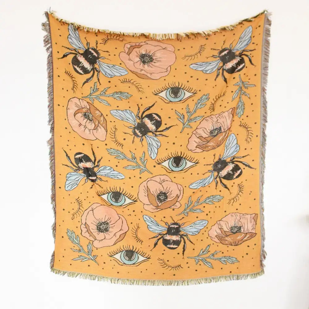 Mustard-yellow woven geo tassel picnic mat and sofa cover with bee poppy and teal eye pattern on dotted background