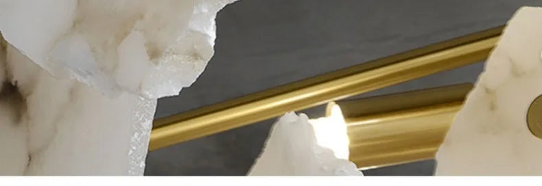 Gold-toned cylindrical rods resting against white marble crystalline rock in a marble led chandelier round pendant light