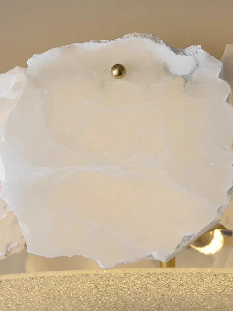 A white translucent geode slice with a golden sphere in the center in a marble led chandelier round pendant light