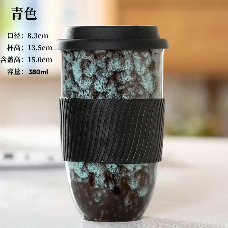 Marbled decorbites ceramic kiln mug with teal and dark brown glaze, black silicone grip, and matching black lid for travel use