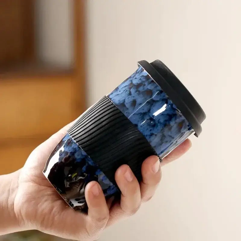 A glossy blue decorbites ceramic kiln mug with black silicone grip and lid for kitchen travel use
