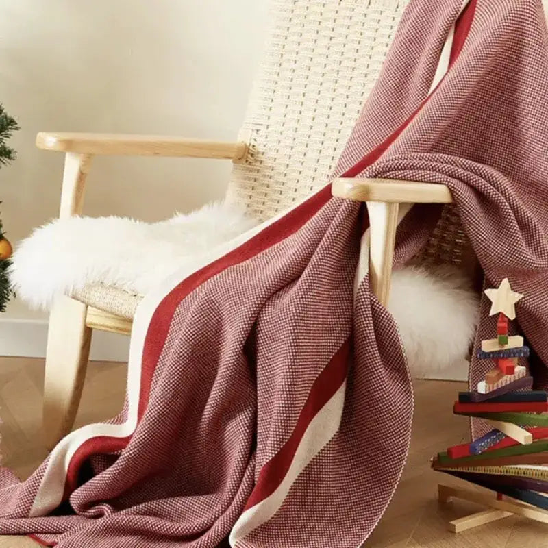 Maroon and red cozy striped knit blanket with bold cream stripes draped on wicker chair decorbites cozy striped throw