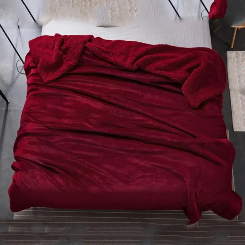 A maroon and white decorbites cozy plush fleece blanket with a soft textured surface draped over a bed