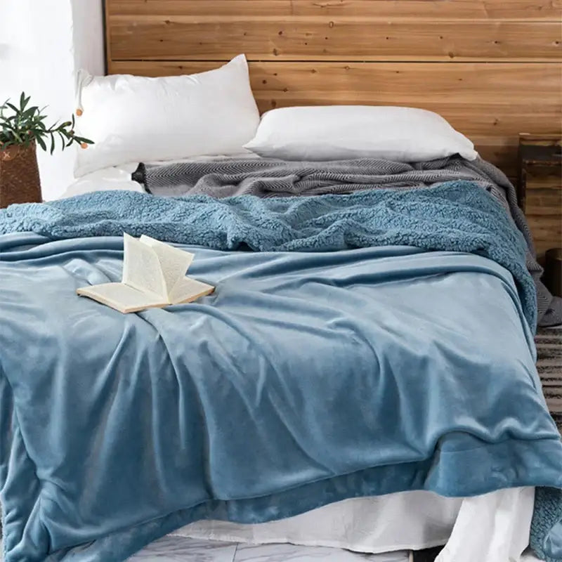 Soft blue plush throw blanket draped over bed from decorbites cozy plush maroon and white sherpa blanket collection