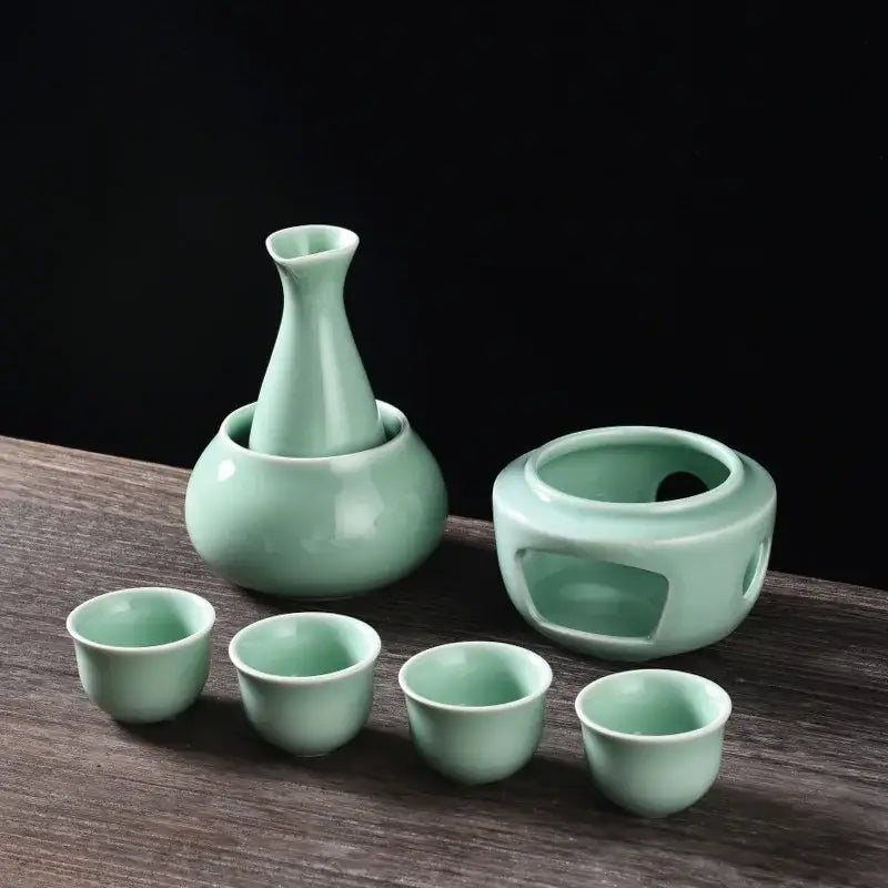 A decorbites ceramic sake set featuring celadon slender vase four cups and an open warming vessel in matte black and light blue