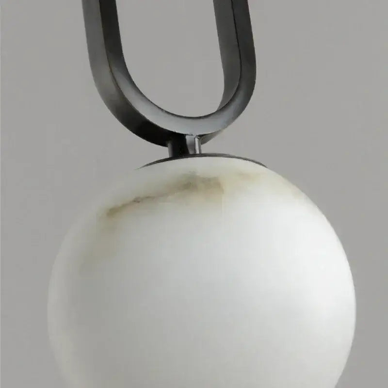 Matte black and polished copper pendant light with a u-shaped metal fixture and marble pendant light orb for dining room