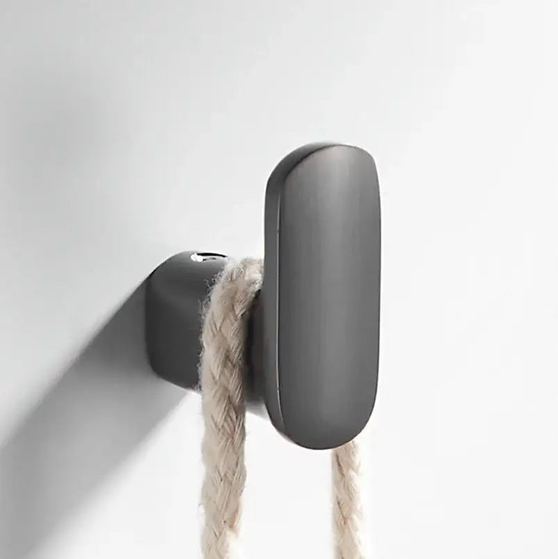 Matte black brass gray deer hook with sleek elongated oval shape holding light beige braided rope for entryway decorbites brass gray