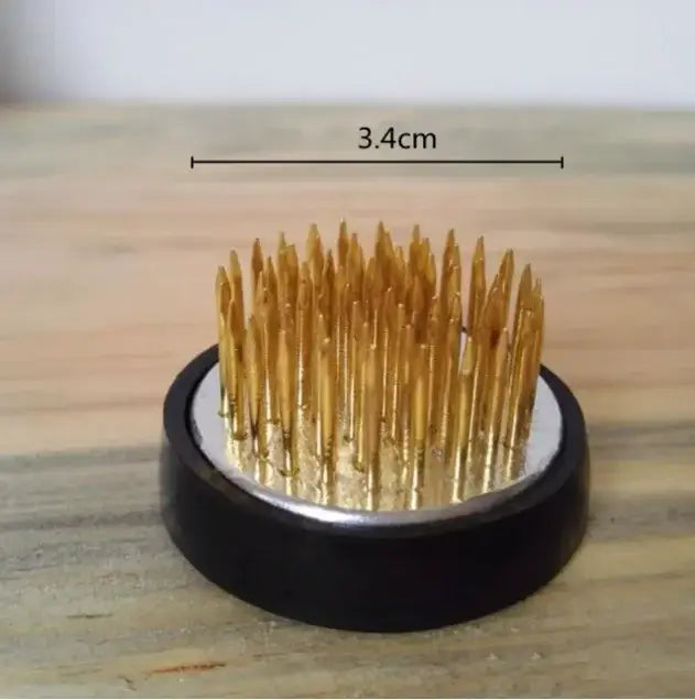 Golden sewing needles arranged upright in a circular black base with silver ring in decorbites ceramic vase sword mountain set