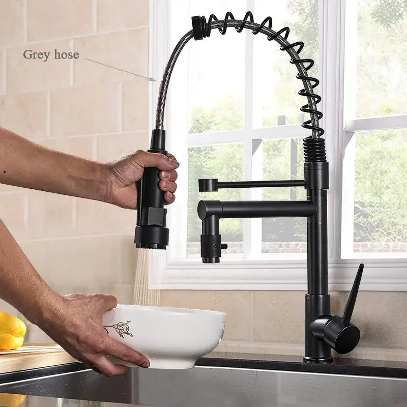 Matte black decorbites brass kitchen faucet with swivel spout and coiled spring hose in a modern design