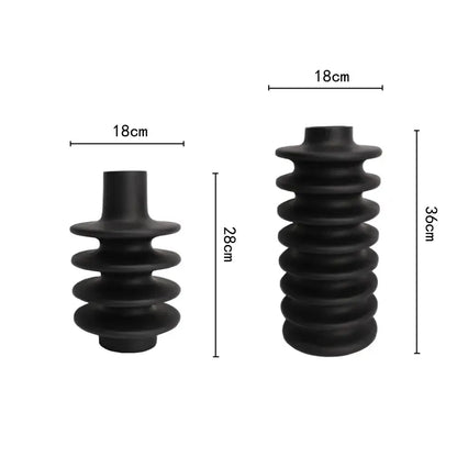 Black rubberized insulated electrical bushing with segmented ribbed design and cylindrical ends featuring geometric circle spiral pattern