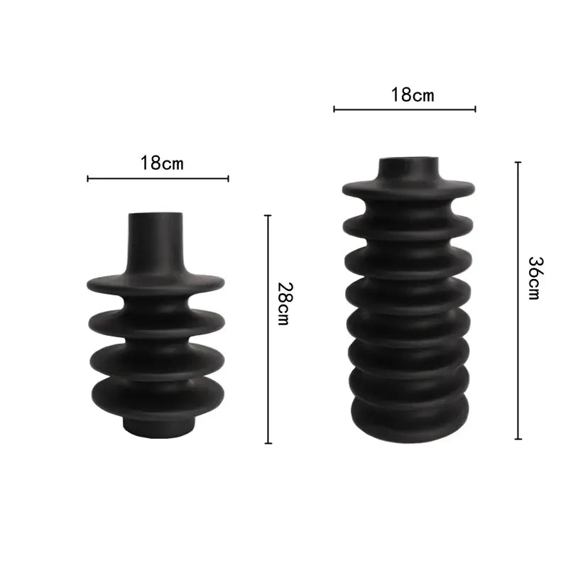 Black rubberized insulated electrical bushing with segmented ribbed design and cylindrical ends featuring geometric circle spiral pattern