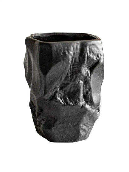 Matte black irregular shaped mouthwash cup with rugged cracked stone texture made from silicone mold by decorbites