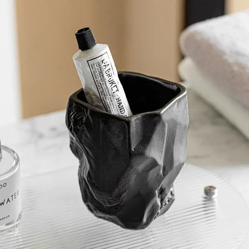 Matte black irregular shaped mouthwash cup made from silicone mold with a textured surface resembling crumpled stone decorbites irregular shaped