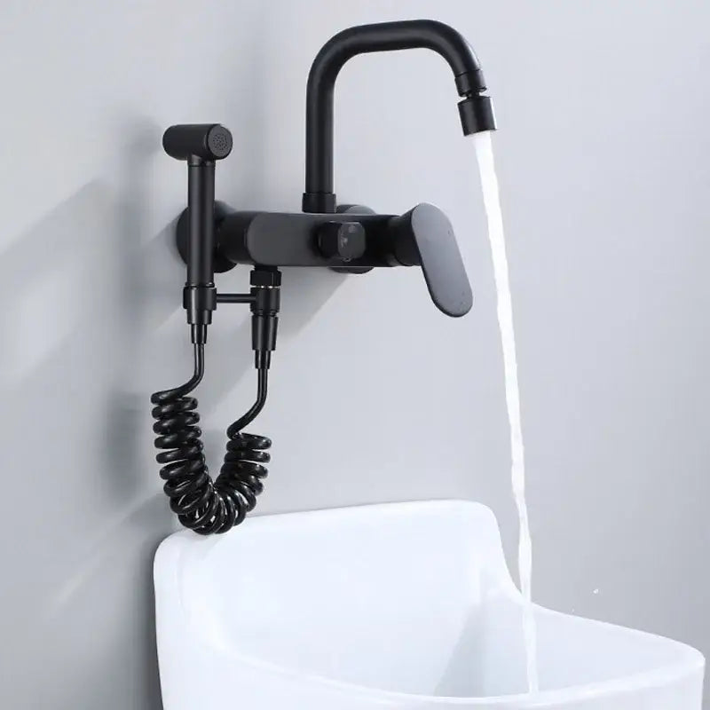 Matte black kitchen mixer tap with wall-mounted curved spout and integrated handheld showerhead on coiled hose