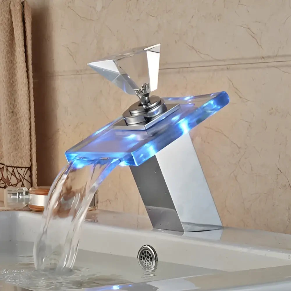 Matte black led waterfall basin faucet with a geometric translucent blue acrylic spout and faceted crystal handle