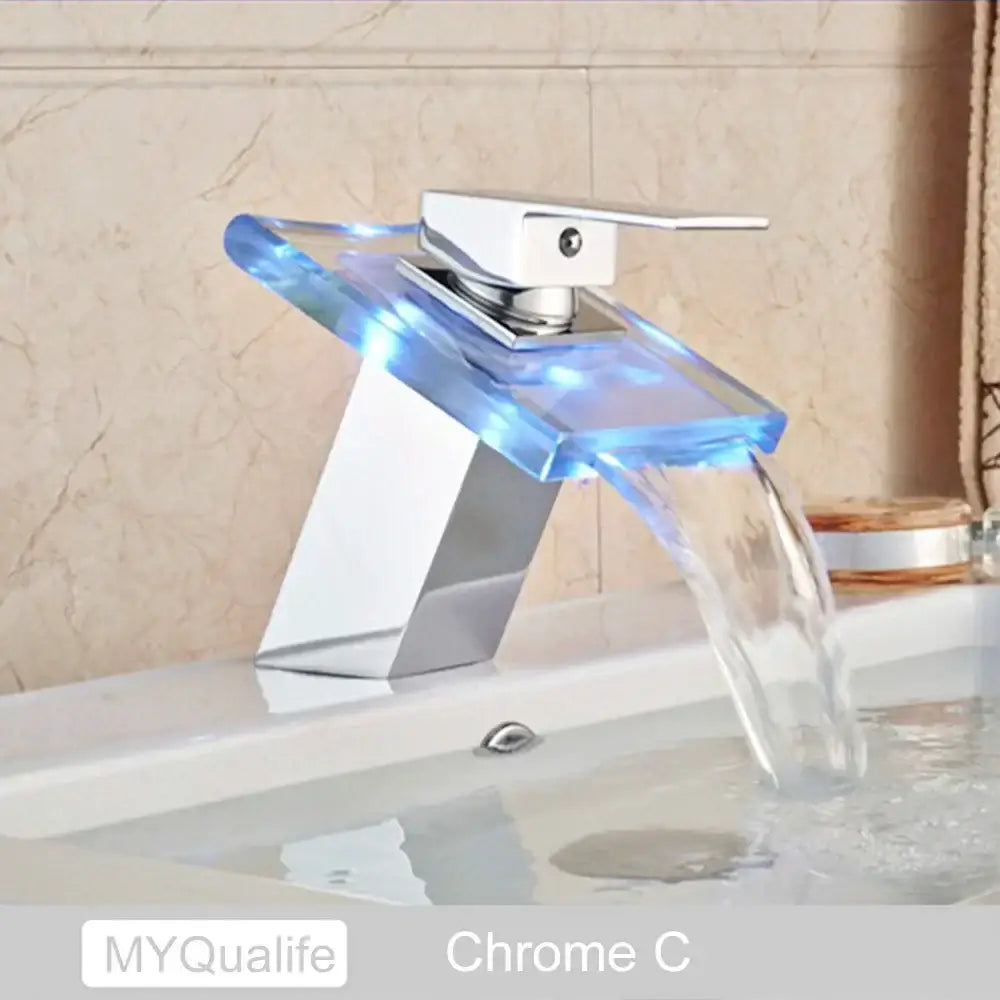 A modern chrome basin faucet with translucent blue glass spout and integrated led lighting decorbites led waterfall basin