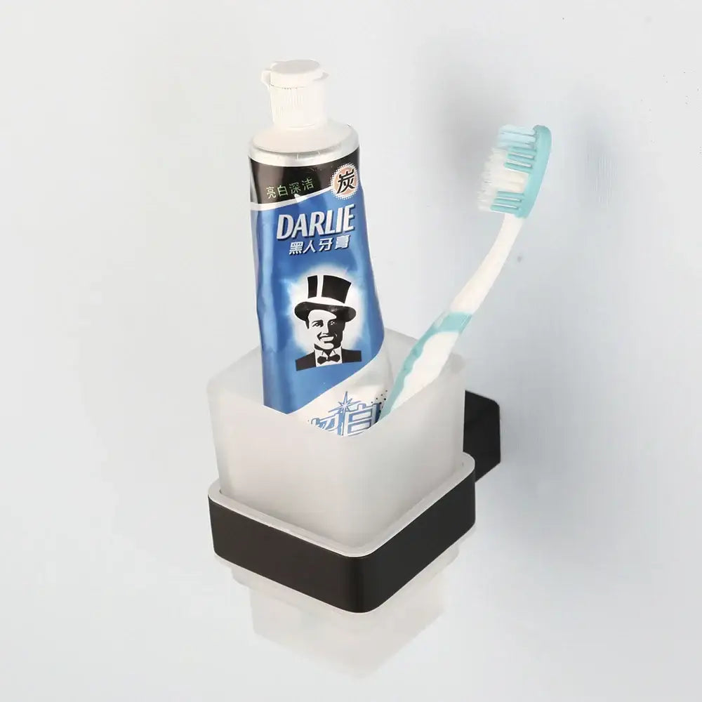 Matte black stainless steel bathroom hardware set featuring a sleek two-toned toothbrush and toothpaste holder with frosted glass