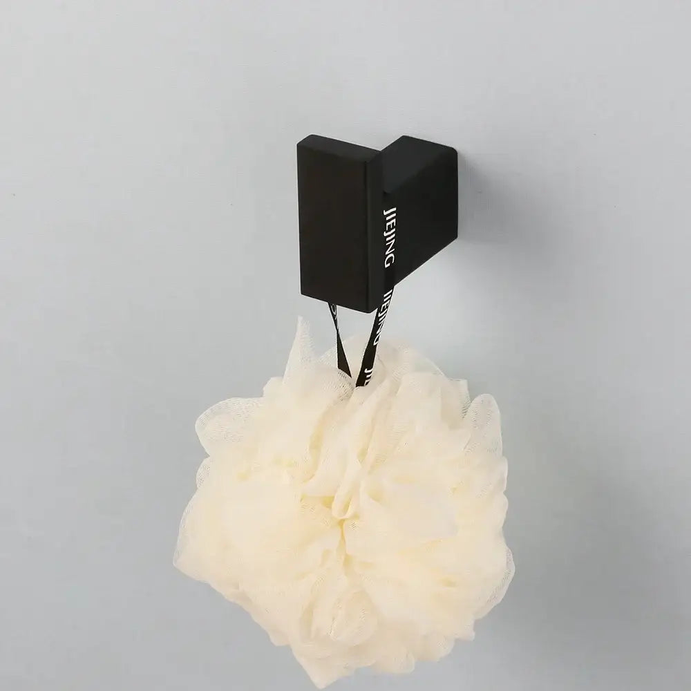 Cream-colored fluffy mesh loofah hanging on a matte black stainless steel bathroom hardware set wall-mounted hook