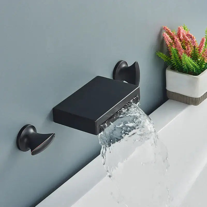 Matte black wall mounted waterfall bathroom faucet with sleek rectangular spout and dual matching handles