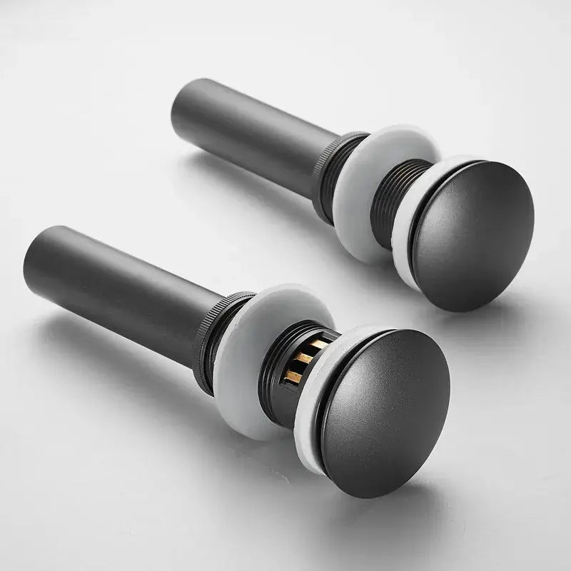 Matte black bathroom sink drain stoppers with white rubber seals and metal stems in brushed gold drain assembly kit
