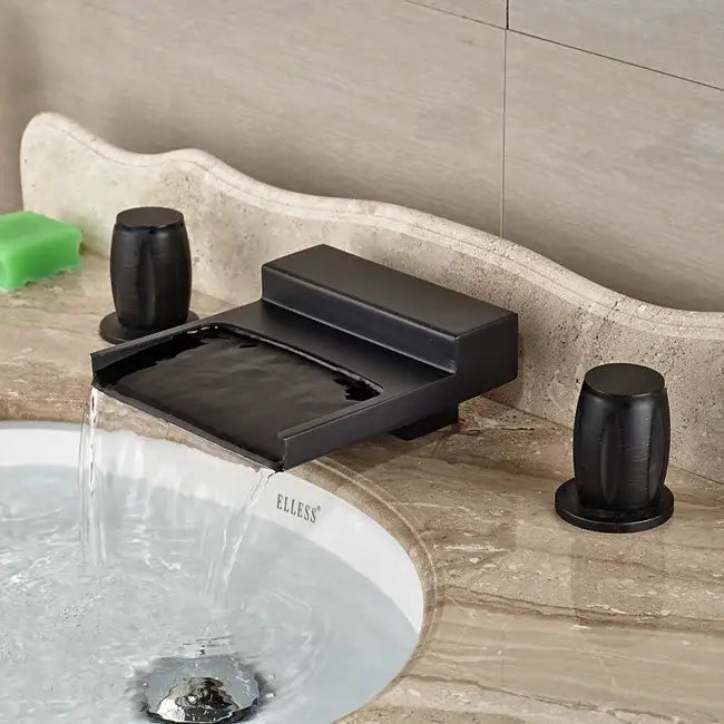 Matte black wide waterfall spout bathroom faucet with square handles and black matte-finish on marble countertop