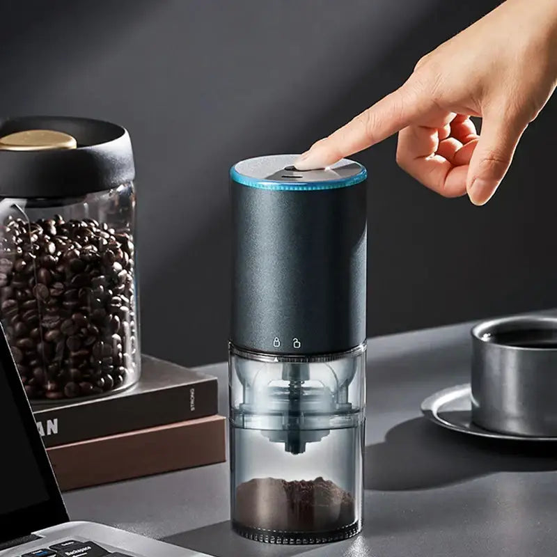 Matte dark teal electric coffee bean grinder with sleek cylindrical design and transparent chamber filled with ground beans