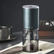 Matte dark teal electric coffee bean grinder with silver accents and transparent chamber for precise grinding