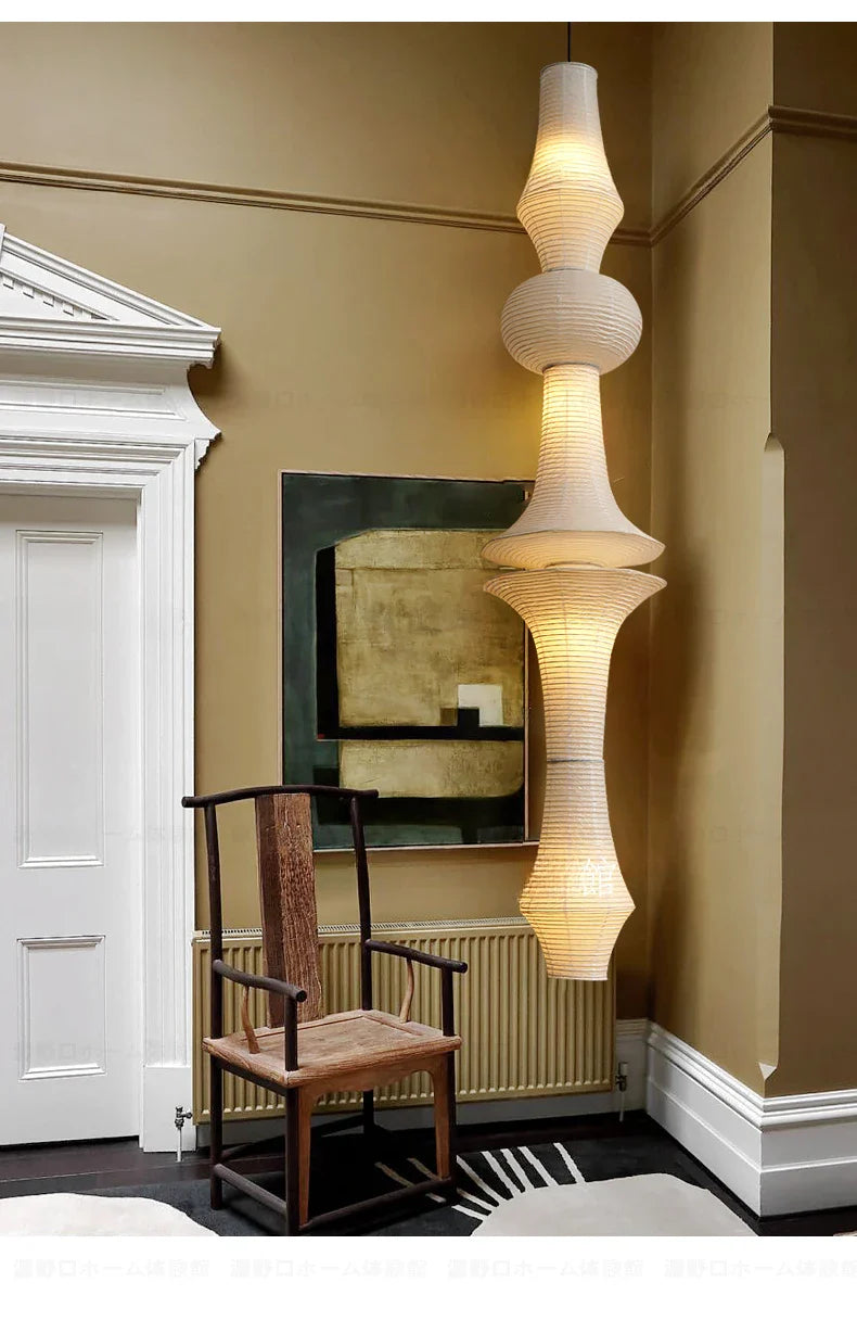A tall cream-colored akari noguchi yong rice paper pendant light with stacked tiers and warm glow for home decor