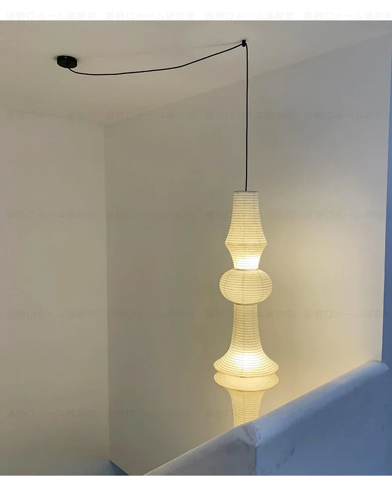 A tall off-white rice paper pendant light with tiered sculptural design in akari noguchi yong style for home decor