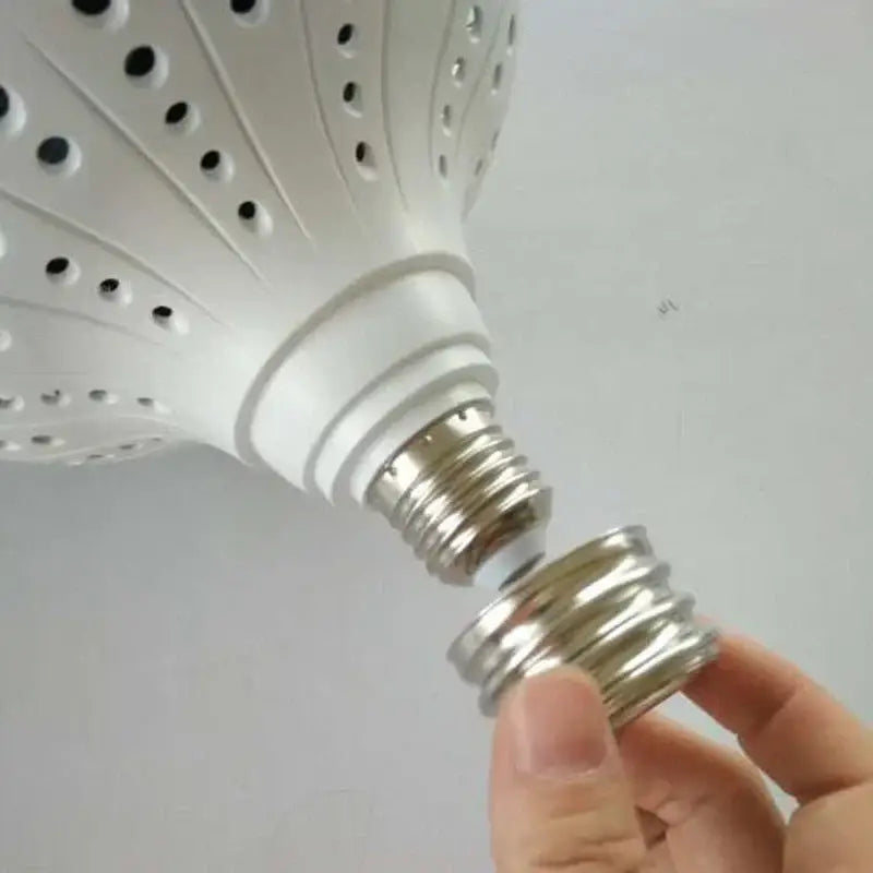 White perforated led bulb with metallic screw base being installed in metallic e40 lamp holder adapter for workshop lighting