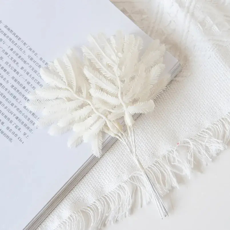 A delicate white artificial fern with feathery fronds in metallic gold and silver palm leaves decorbites gold palm pins