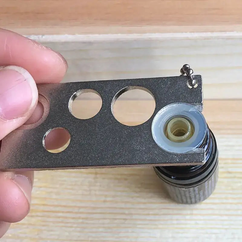 Black metal essential oils opener tool with circular cutouts and cylindrical component for decorbites essential oils storage
